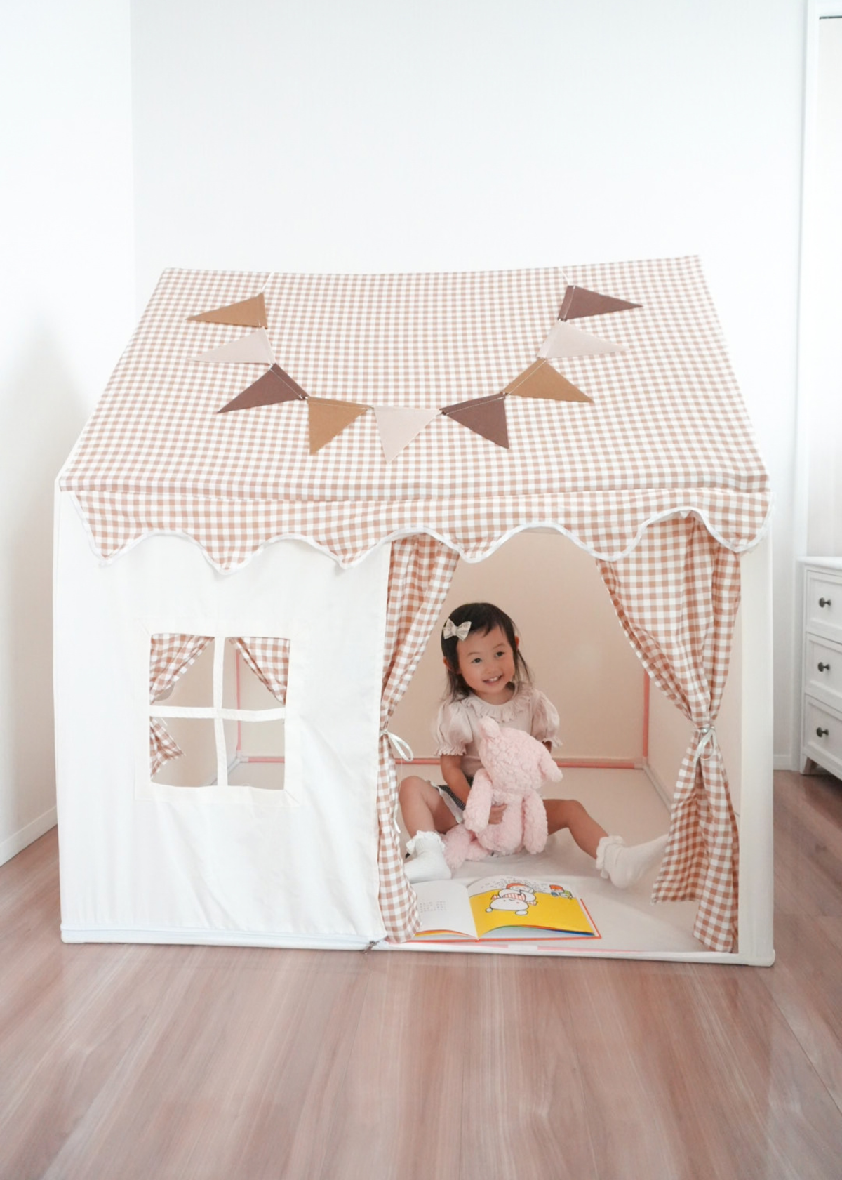 ハウス型キッズテントの入口に座る子ども カーテンと窓付きの室内テント