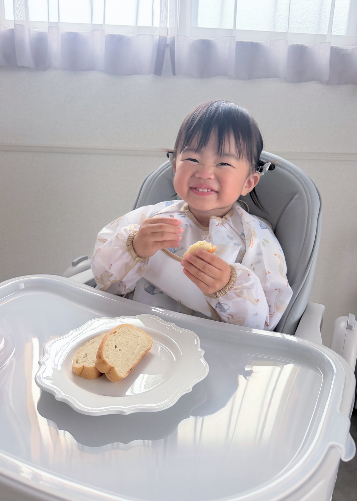 子どもが長袖お食事エプロンを着用してパンを食べている使用イメージ