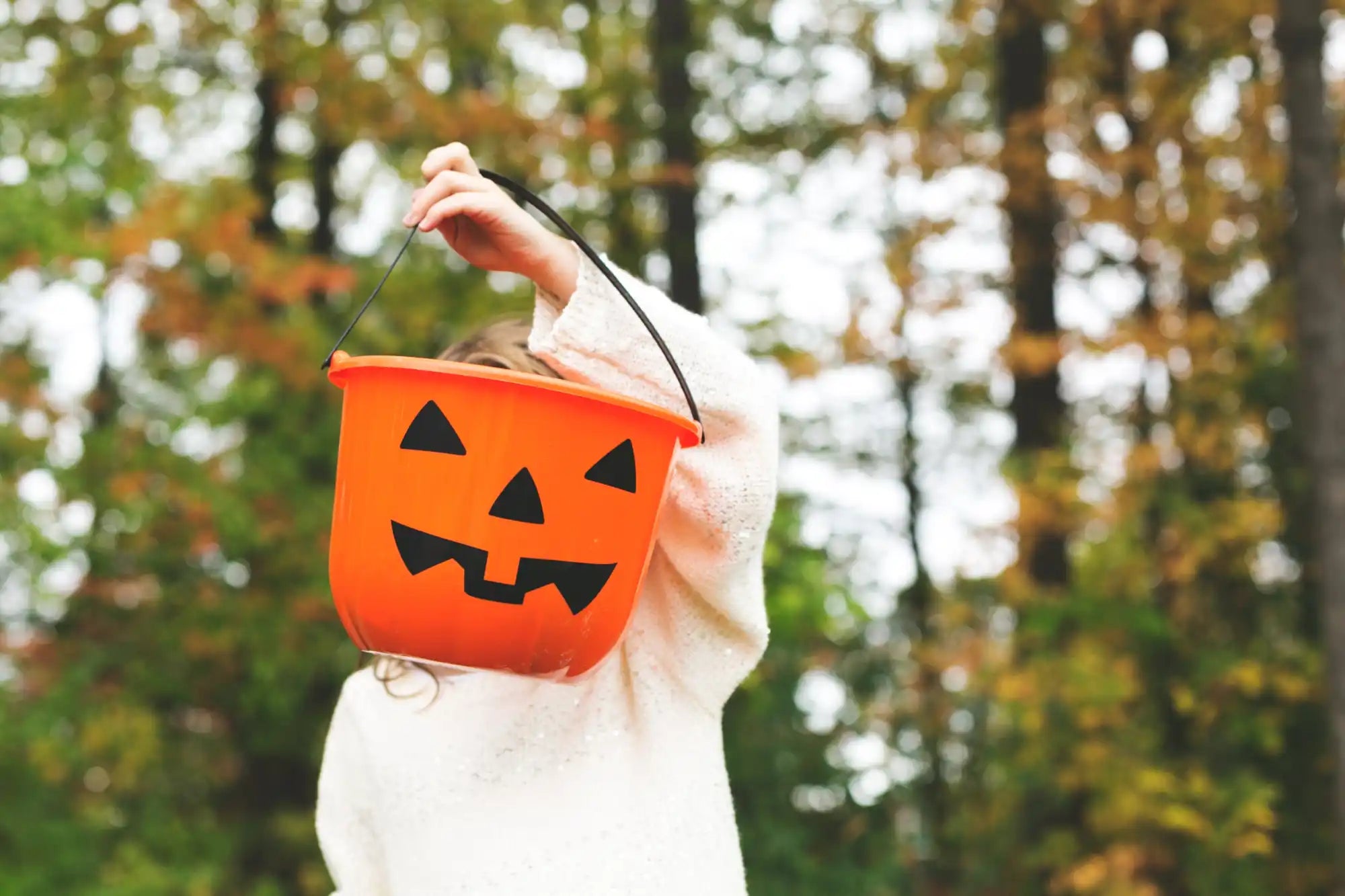 ジャック・オー・ランタンの顔がついたオレンジ色のプラスチック製ハロウィンお菓子バケツ。