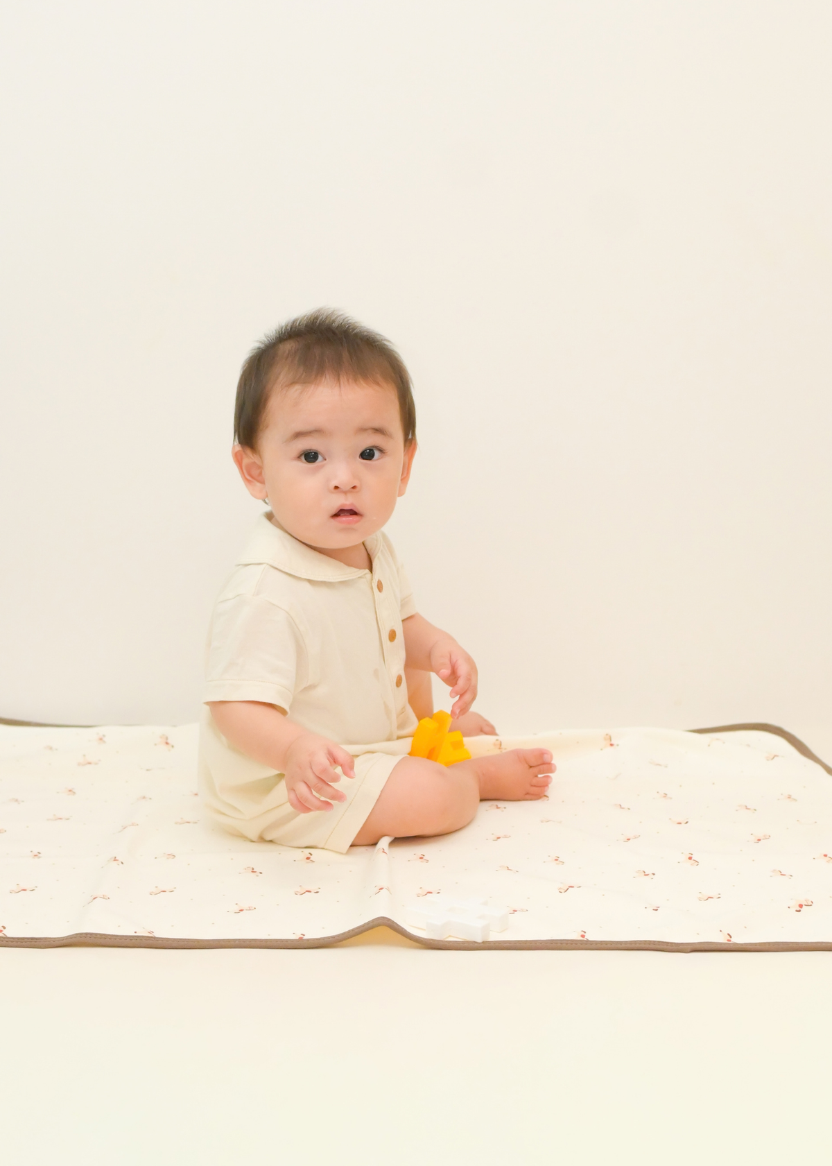 ベビーキッズ防水シーツの上に赤ちゃんが座っている使用イメージ。ガーゼ素材のやわらかな寝具