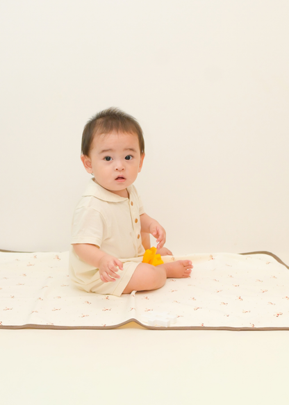 ベビーキッズ防水シーツの上に赤ちゃんが座っている使用イメージ。ガーゼ素材のやわらかな寝具