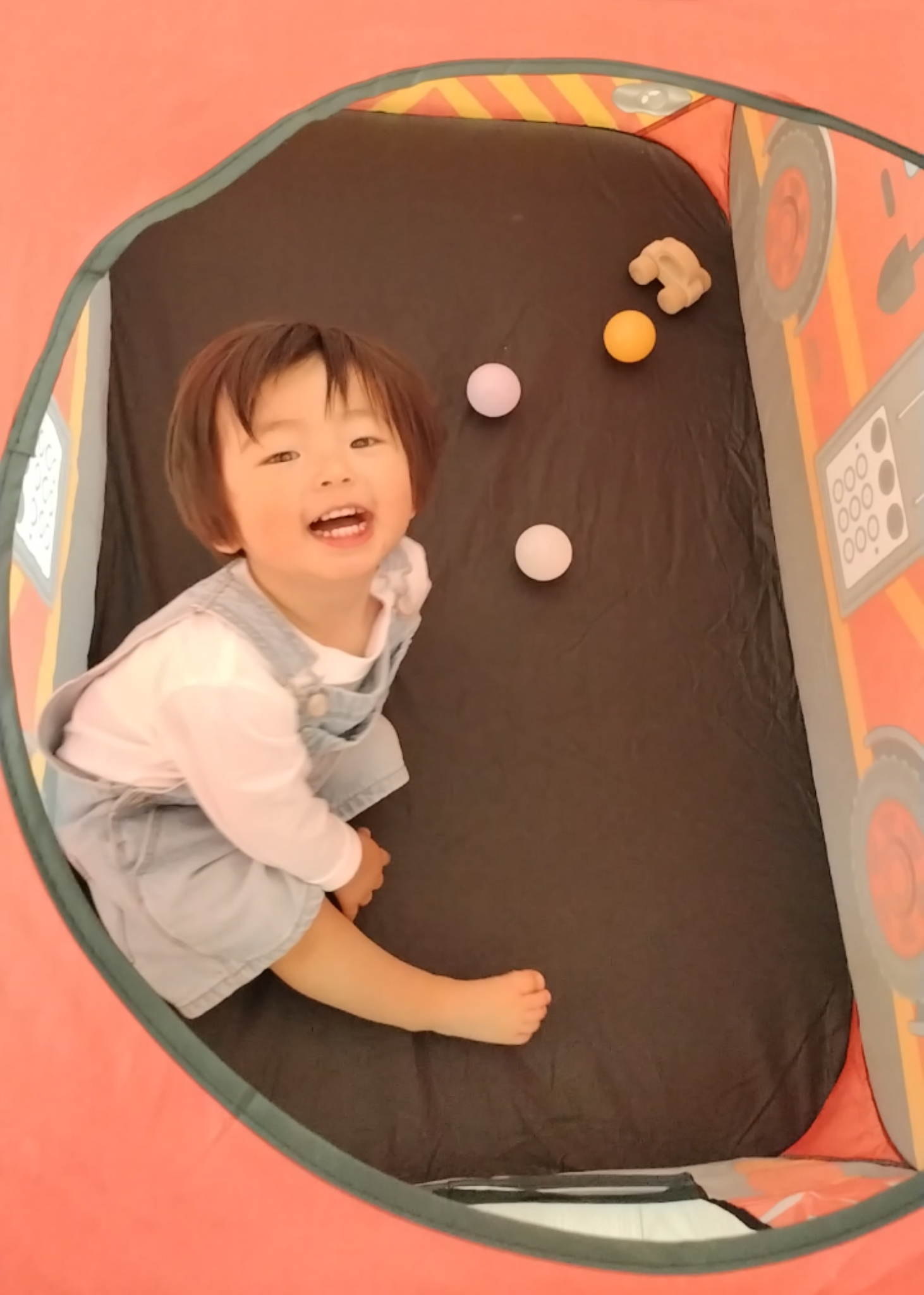 キッズテントの中で子どもが遊んでいる様子。天窓から顔を出せる乗り物デザインのプレイテント