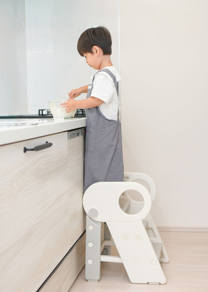 子どもがキッチンでお手伝いをしている使用イメージ。2段・3段可変式踏み台に立って作業する様子