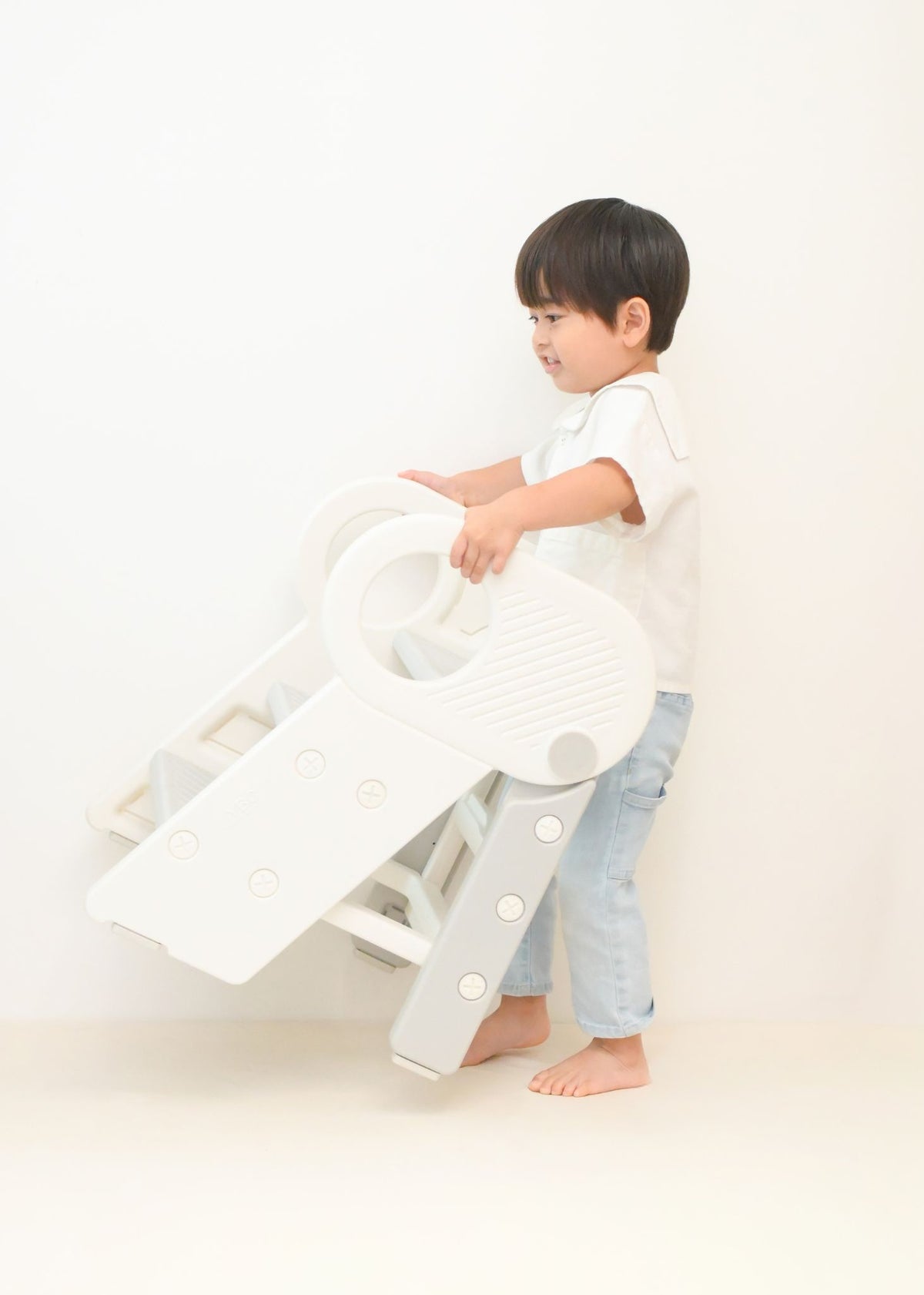 男の子が2段・3段可変式踏み台を使って洗面台に手を伸ばしている使用イメージ。左右ハンドルで支えやすい設計