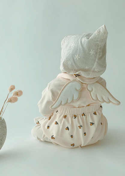 天使の羽付き汗取りパッドを着用した赤ちゃんの後ろ姿。花柄のワンピースと合わせた使用イメージ
