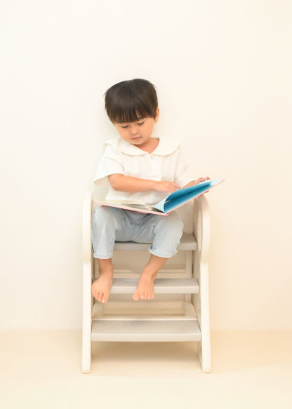 男の子が2段・3段可変式踏み台に座りながら本を読んでいる使用イメージ