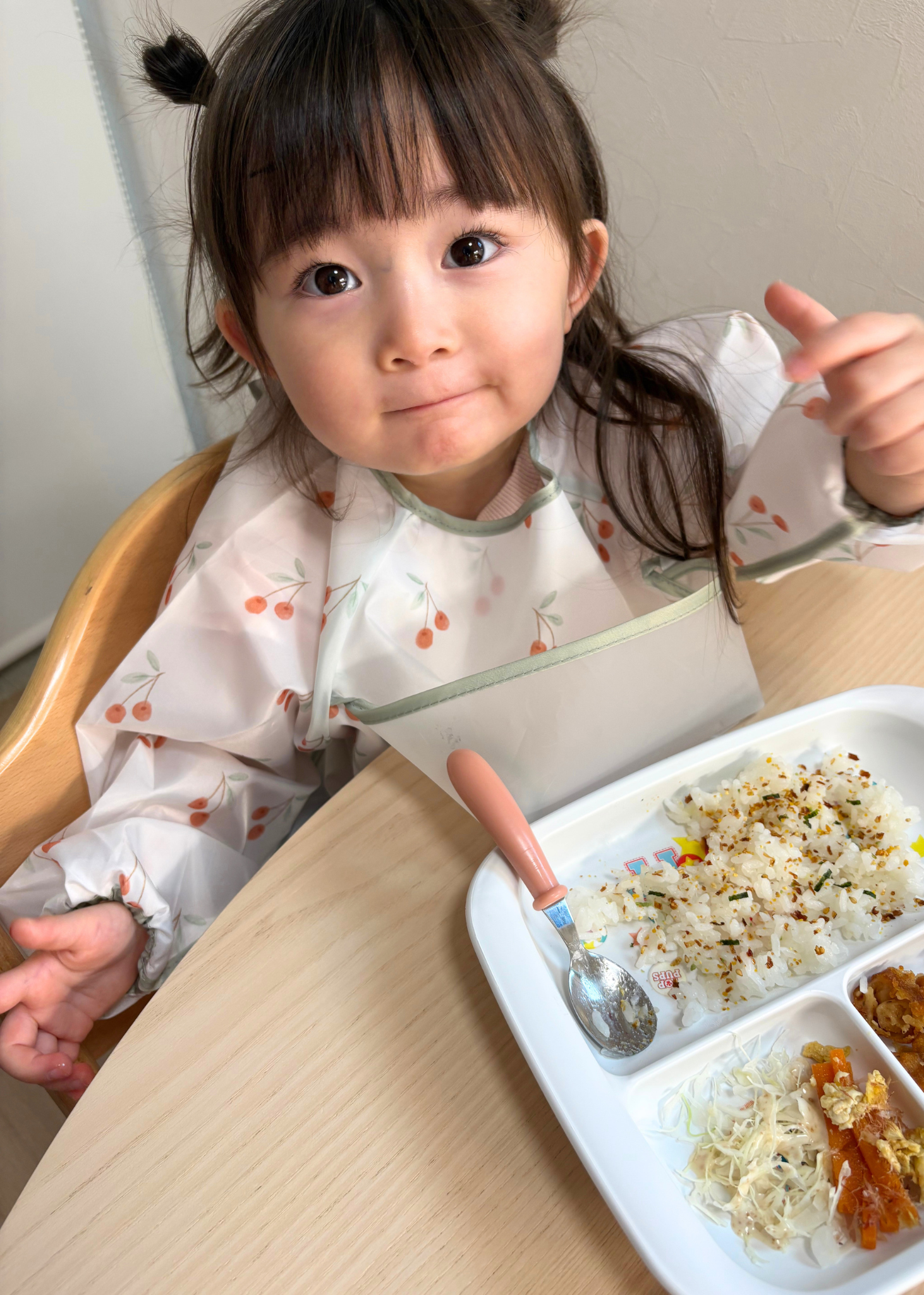 女の子が花柄の長袖お食事エプロンを着用して食事をしている使用イメージ