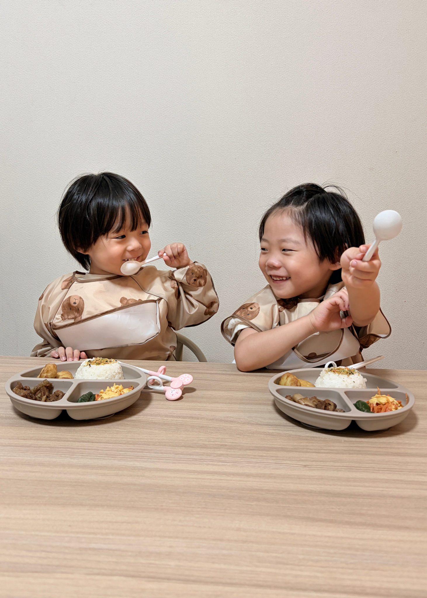 2人の子どもが長袖お食事エプロンを着用して食事をしている使用イメージ