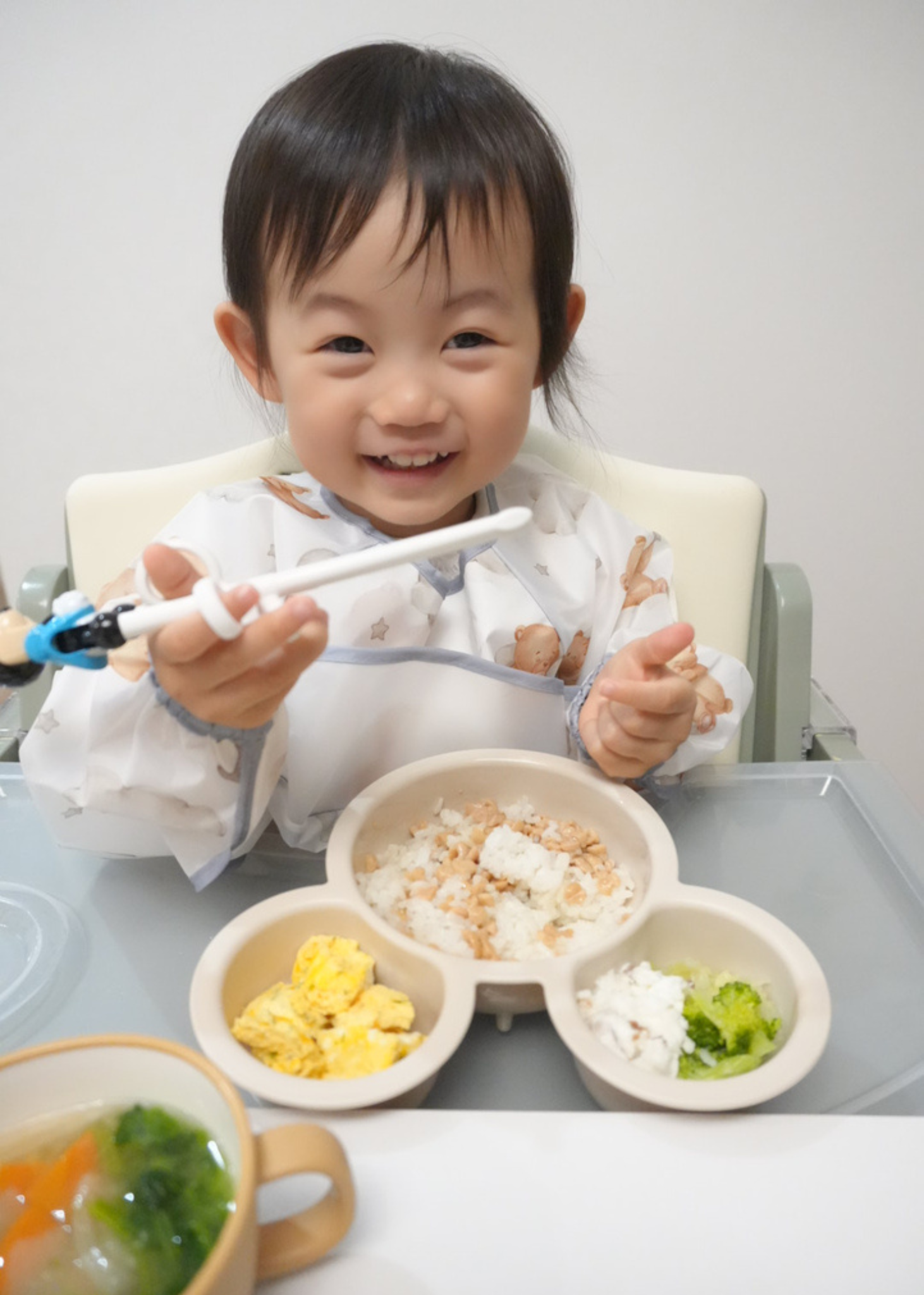 男の子が長袖お食事エプロンを着用し、食べ物を手に持っている使用イメージ