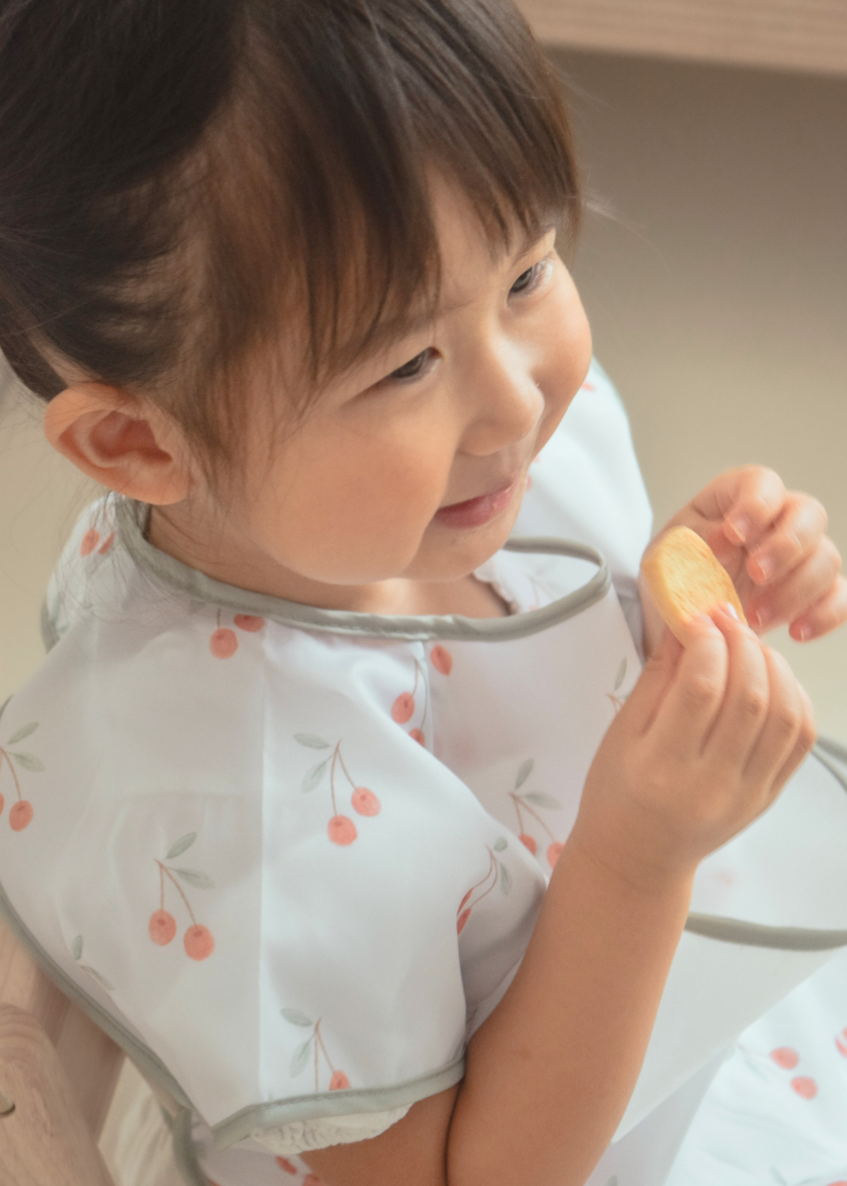 子どもが花柄の半袖お食事エプロンを着用して食事をしている近接使用イメージ