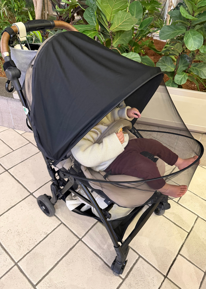 ベビーカー用サンシェードを装着して赤ちゃんが乗っている屋外使用イメージ。上部カバーで日差しを遮る様子