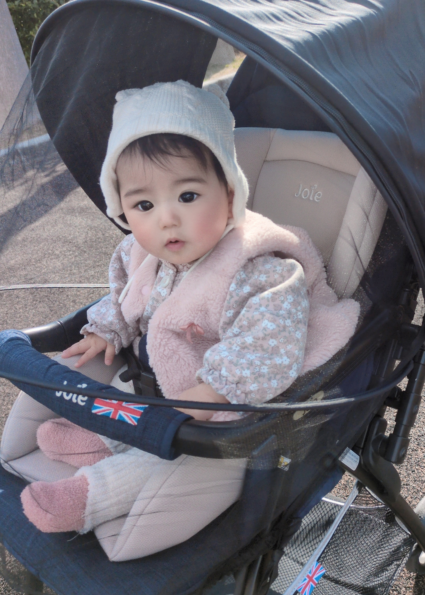 ベビーカーサンシェードの中で赤ちゃんが座っている近接使用イメージ。顔が見えるメッシュ窓を備えた設計