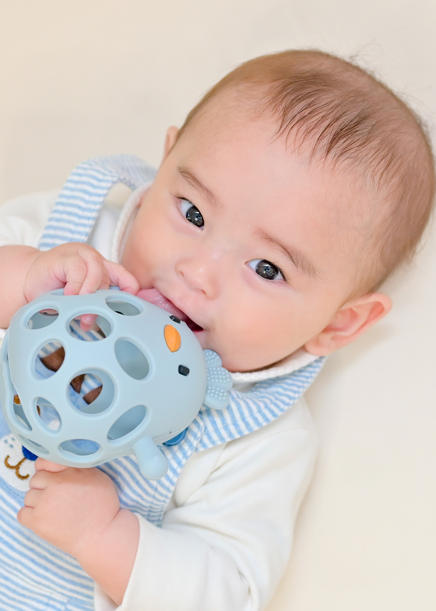 赤ちゃんがブルーのボールタイプのベビーシリコン歯がためを噛んでいる使用イメージ。歯固め期の赤ちゃんに使える設計