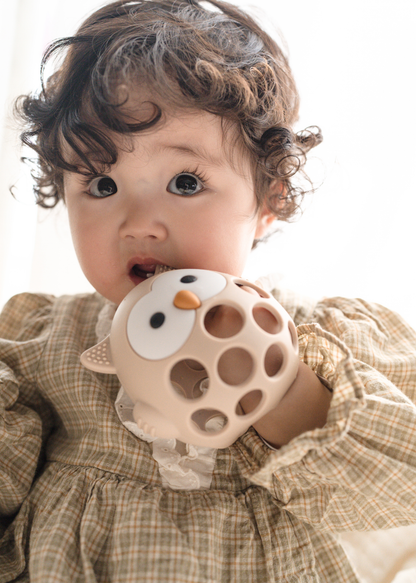 子どもがベージュのフクロウ型ベビーシリコン歯がためを口にしている使用イメージ。穴のある立体形状を紹介