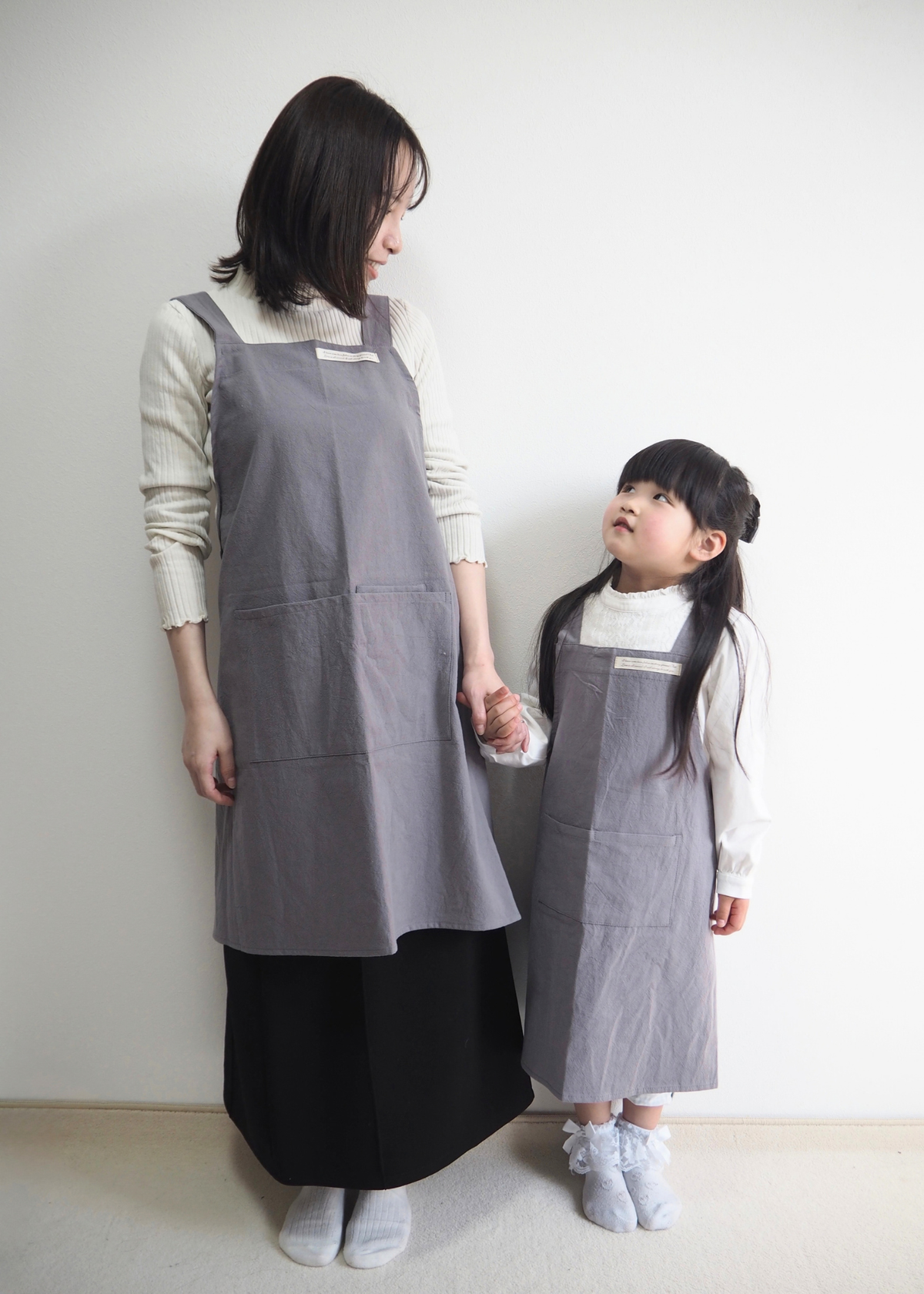 母親と子どもがグレー系のエプロンを着用して並んでいる使用イメージ。親子で揃えられるデザイン