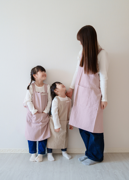 母親と2人の子どもがピンク系のエプロンをお揃いで着用している使用イメージ。親子リンクコーデ