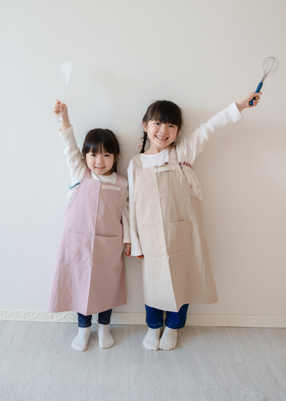 2人の子どもがピンクとベージュのエプロンを着用して並んでいる使用イメージ。きょうだいコーデ