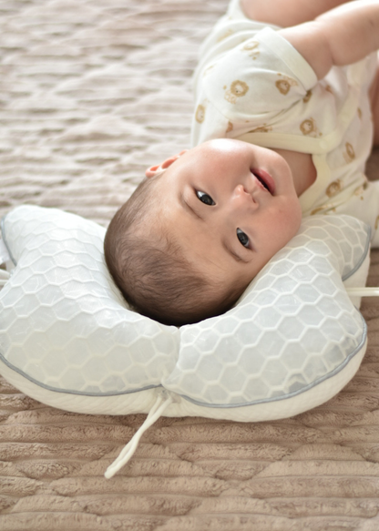 ベビー枕を使用する赤ちゃんのイメージ、白い枕に頭を乗せて横になっている様子