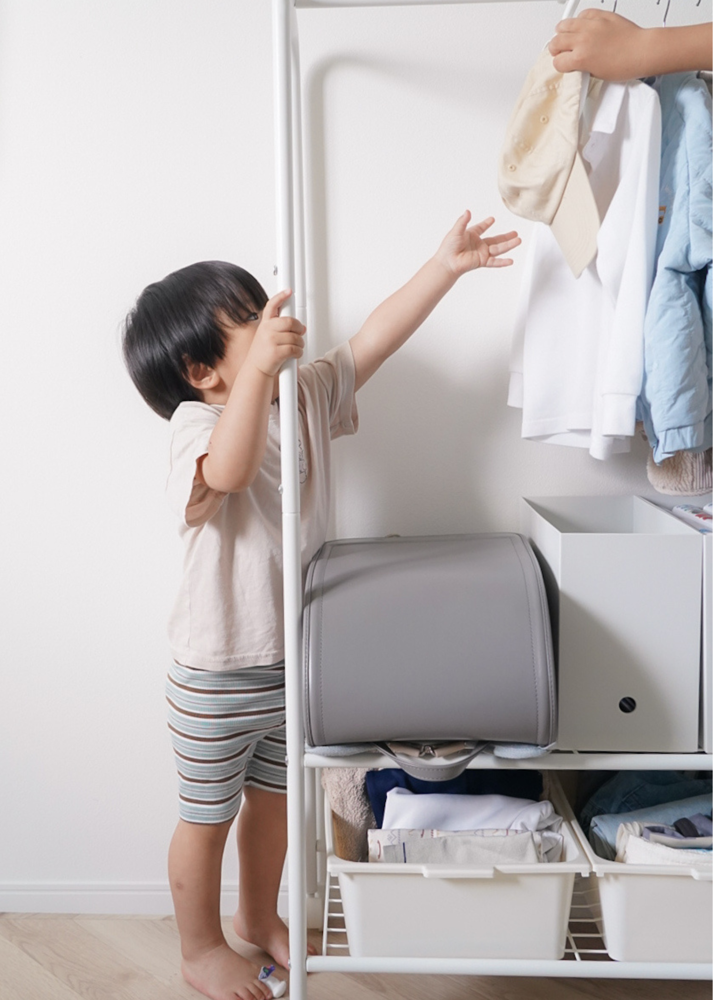 子どもがキッズハンガーラックから帽子を取る様子。自分で身支度しやすい収納ラック