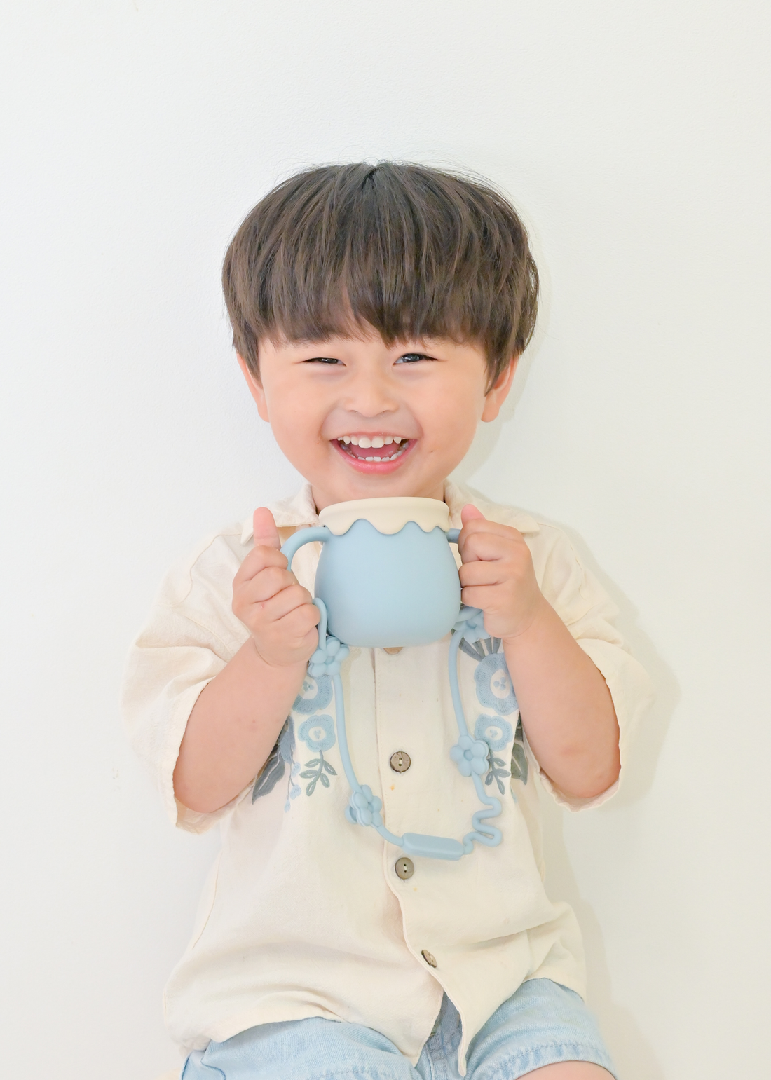 ブルーの3WAYマグを子どもが両手で持っている飲用イメージ。ストローマグとして使用