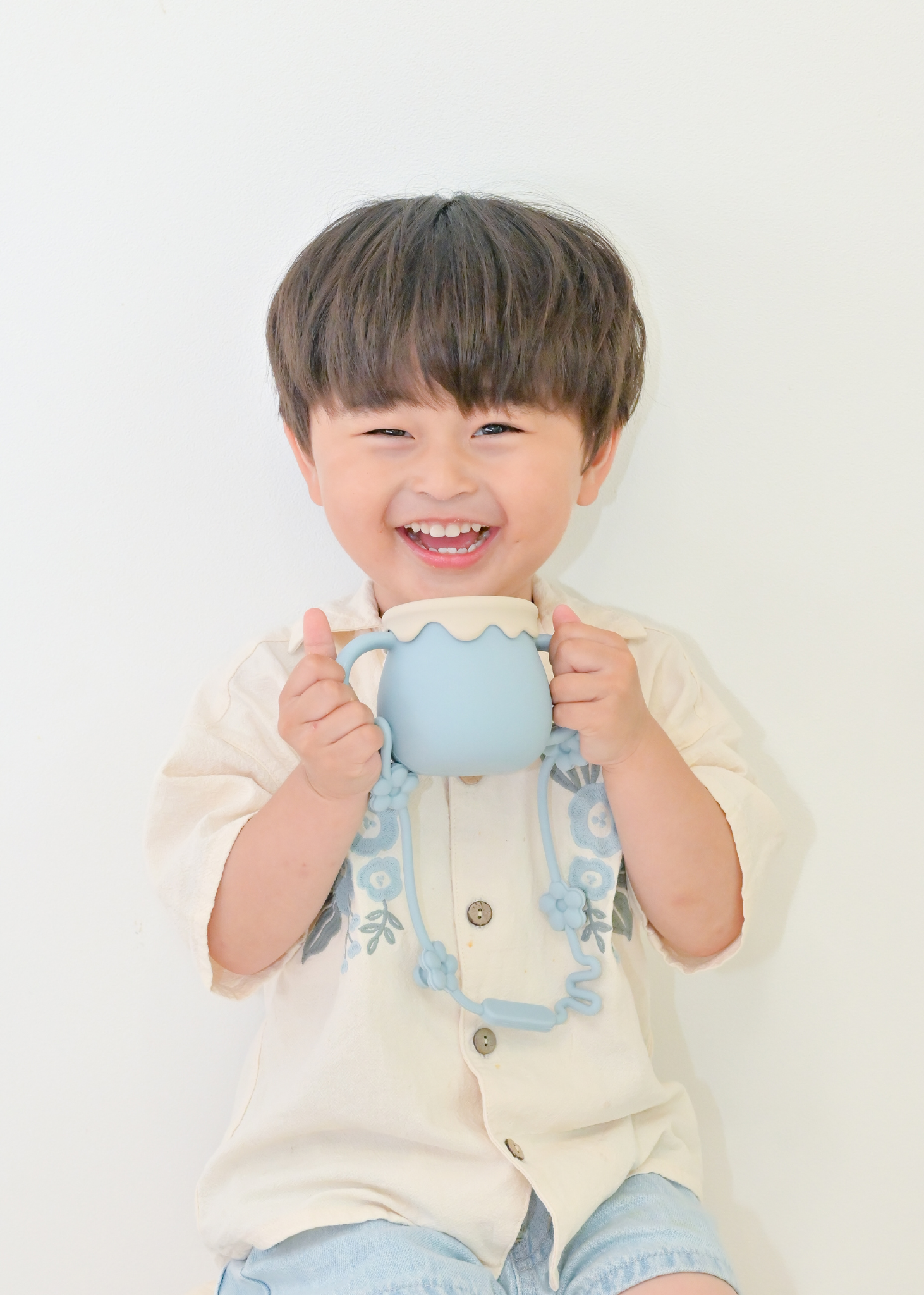 ブルーの3WAYマグを子どもが両手で持っている飲用イメージ。ストローマグとして使用