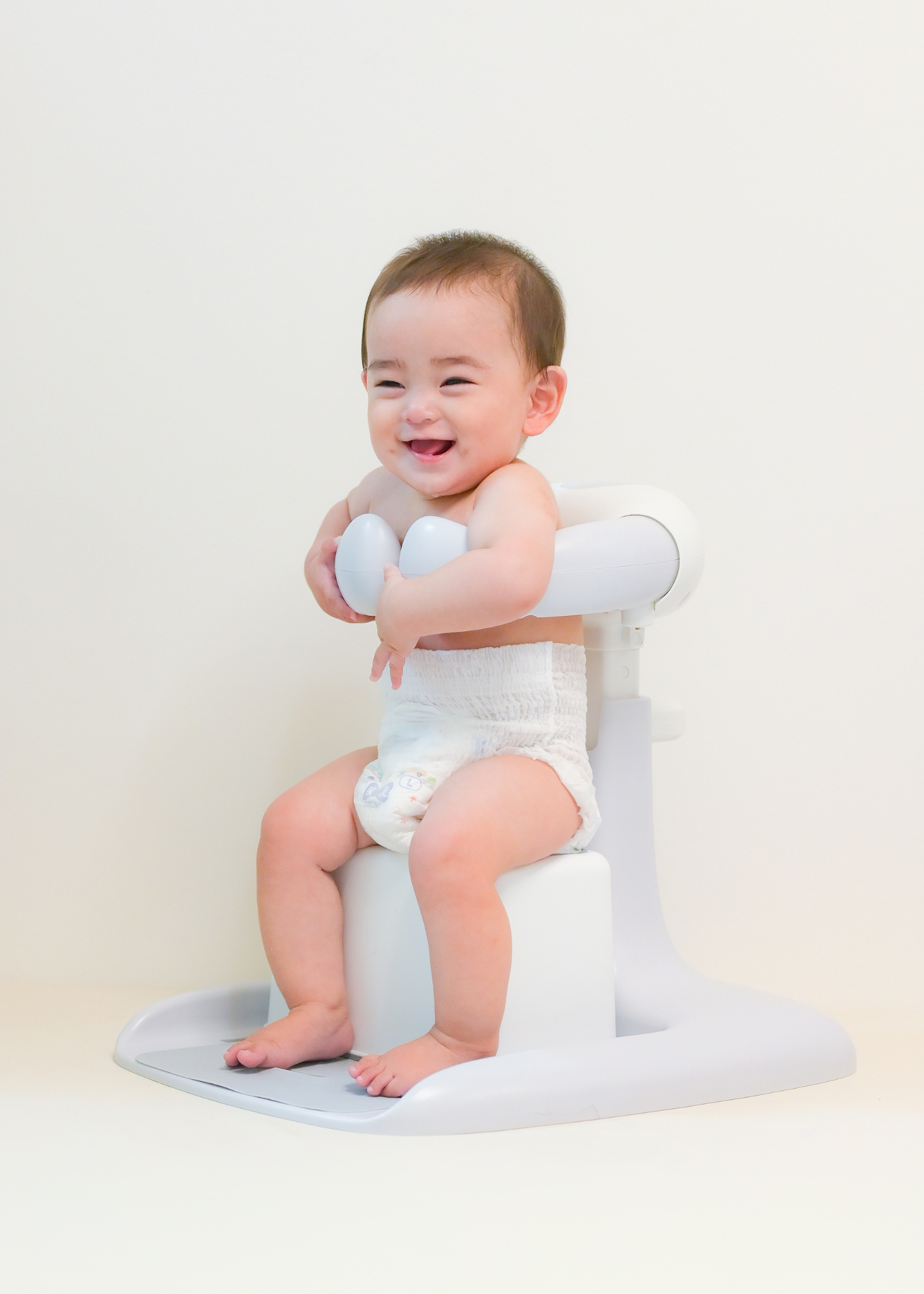 赤ちゃんがホワイトのベビーシャワースタンドに座っている使用イメージ。お風呂で使いやすいサイズ