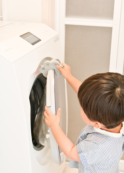 子どもが洗濯機のドア付近で肉球型指挟み防止クッションを使っている使用イメージ