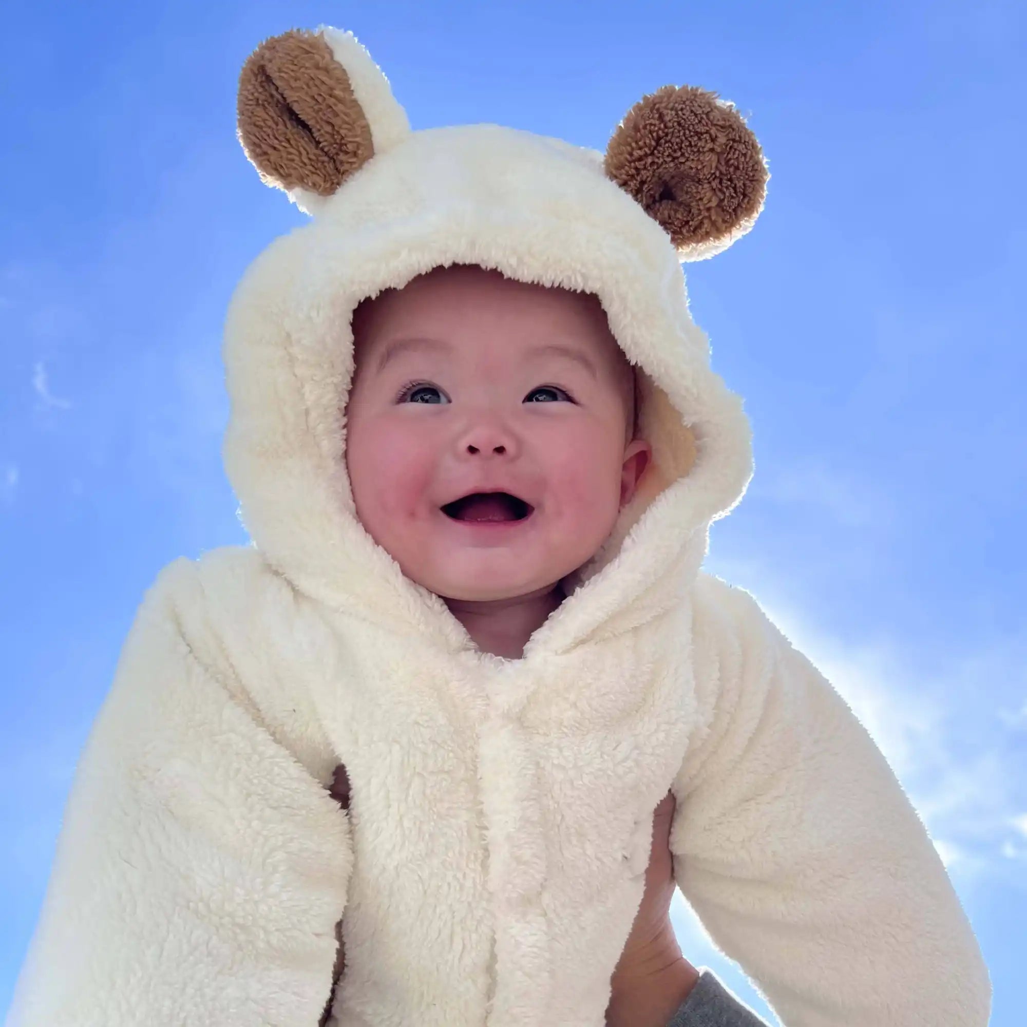白いフード付きフリースベアスーツを着た赤ちゃん。