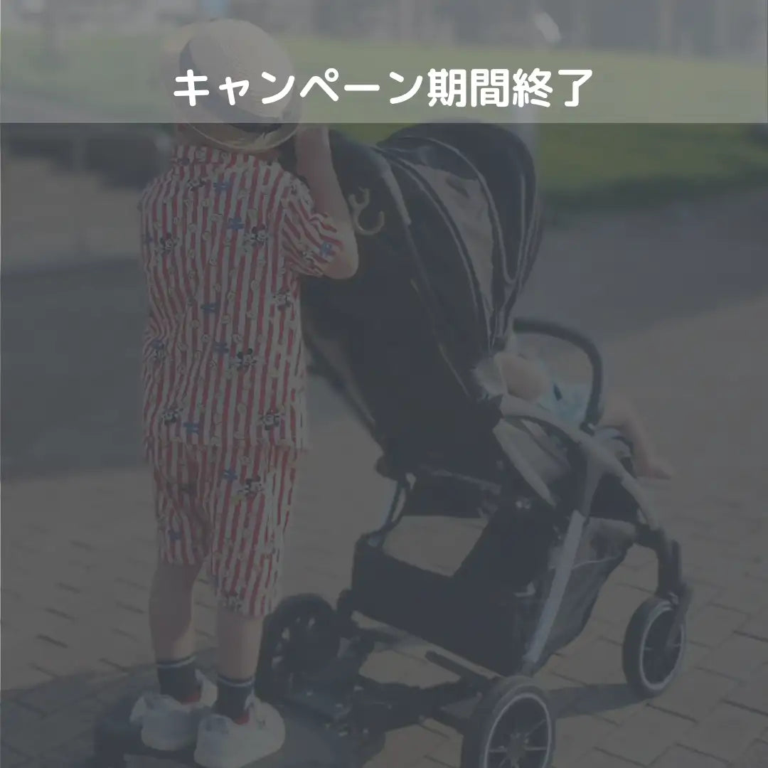 黒と銀色のベビーカーで、中に子供が座っており、キャノピーと四輪付き