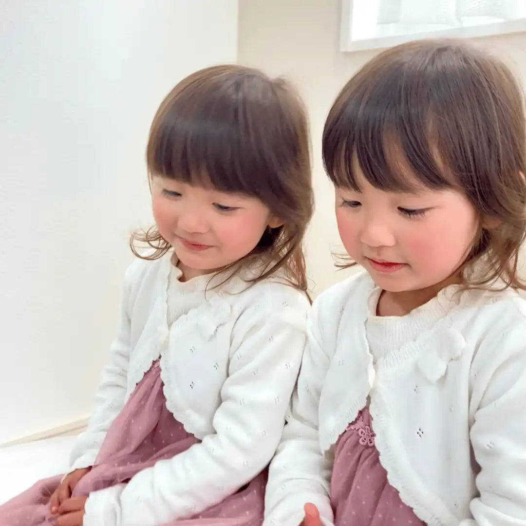 白いカーディガンとピンクのドレスを着た二人の若い女の子。