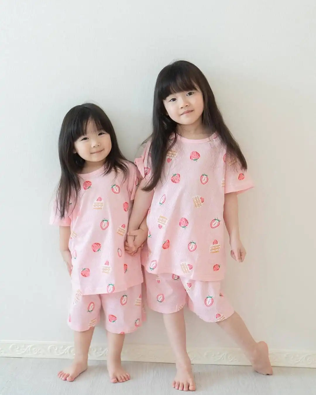 果物柄のピンクのパジャマを着た若い女の子二人