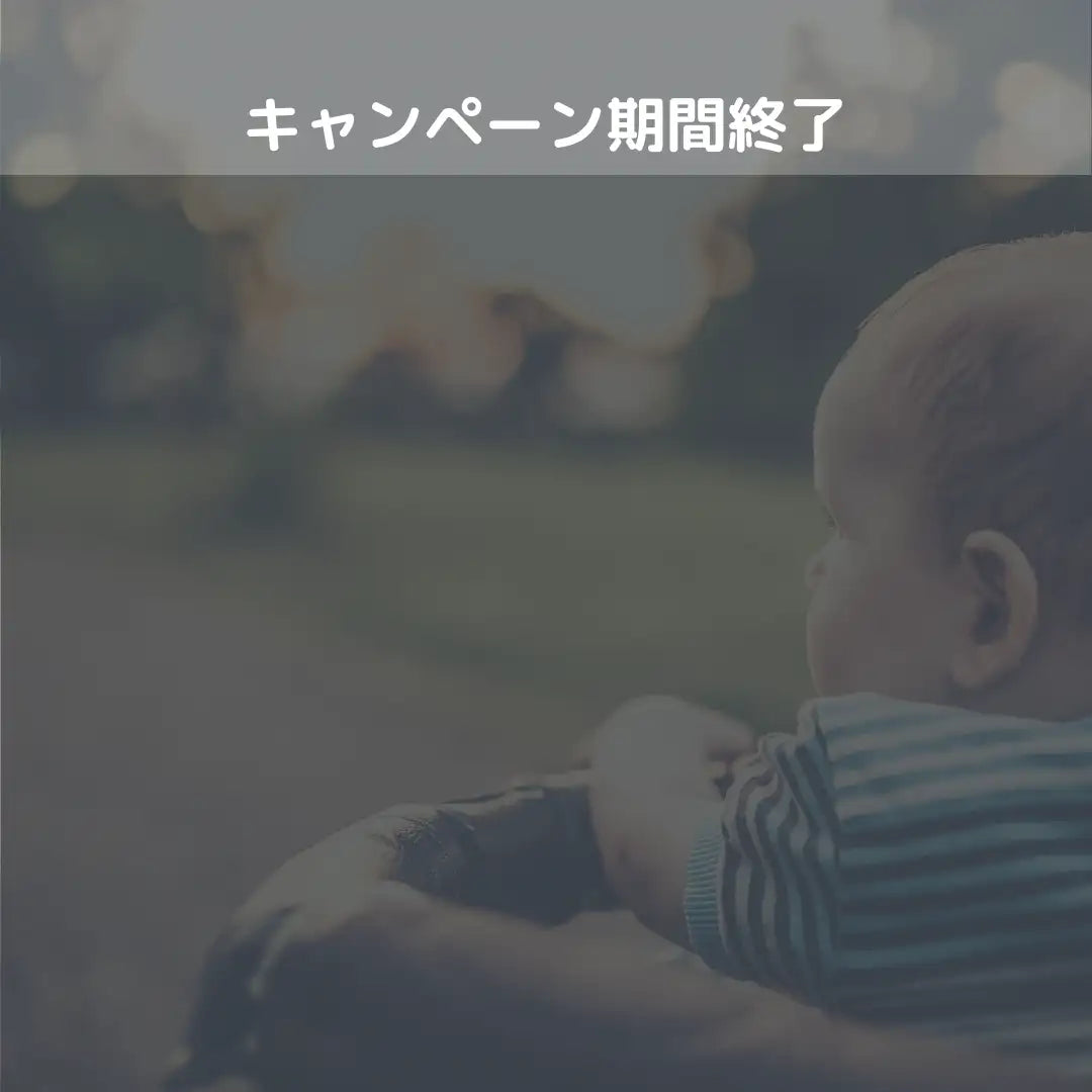 青と白のストライプのシャツを着た赤ちゃんを、誰かの腕に優しく抱かれている。