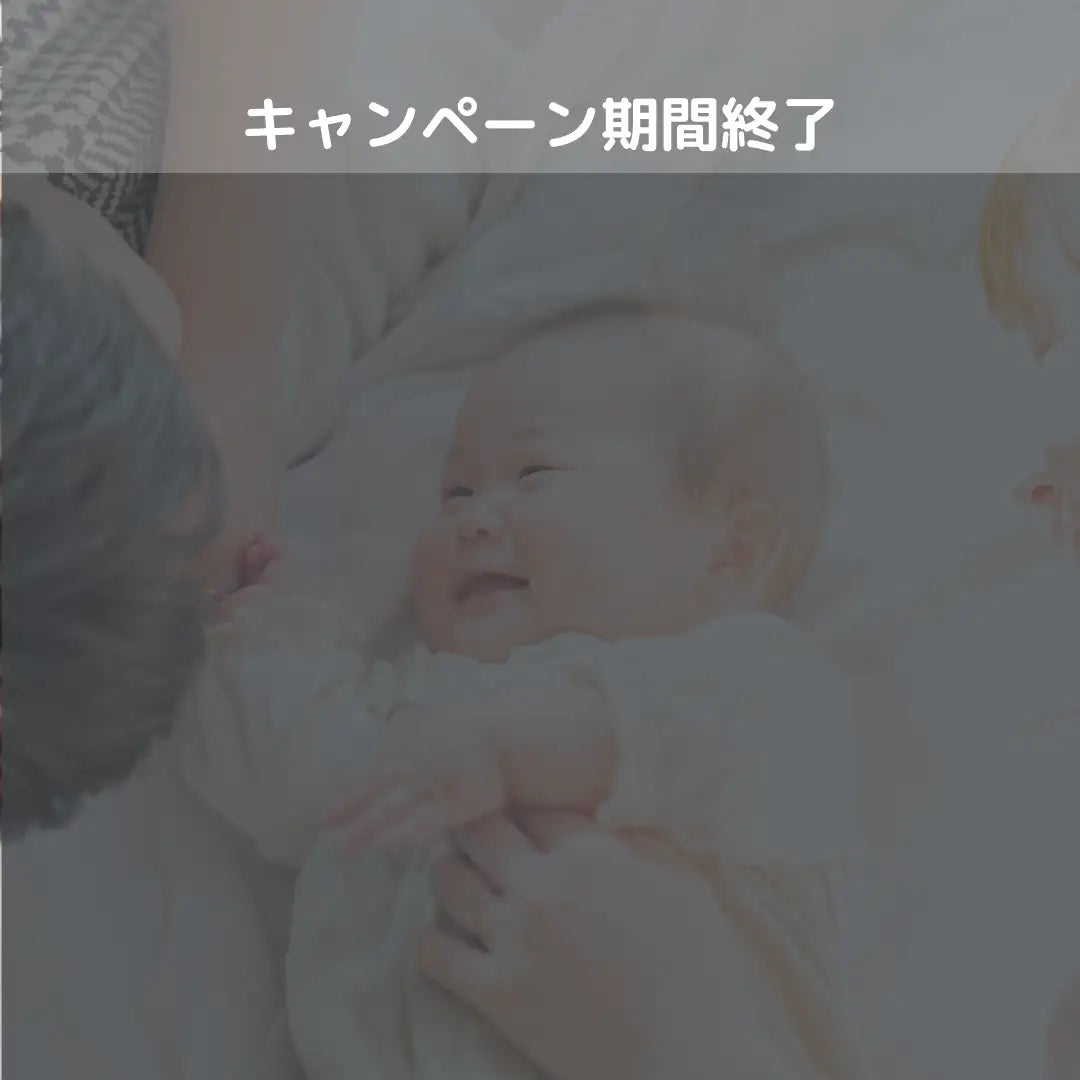 柔らかい白い服を着たにっこり笑う赤ちゃんが、大人の胸に心地よく寄り添っている。