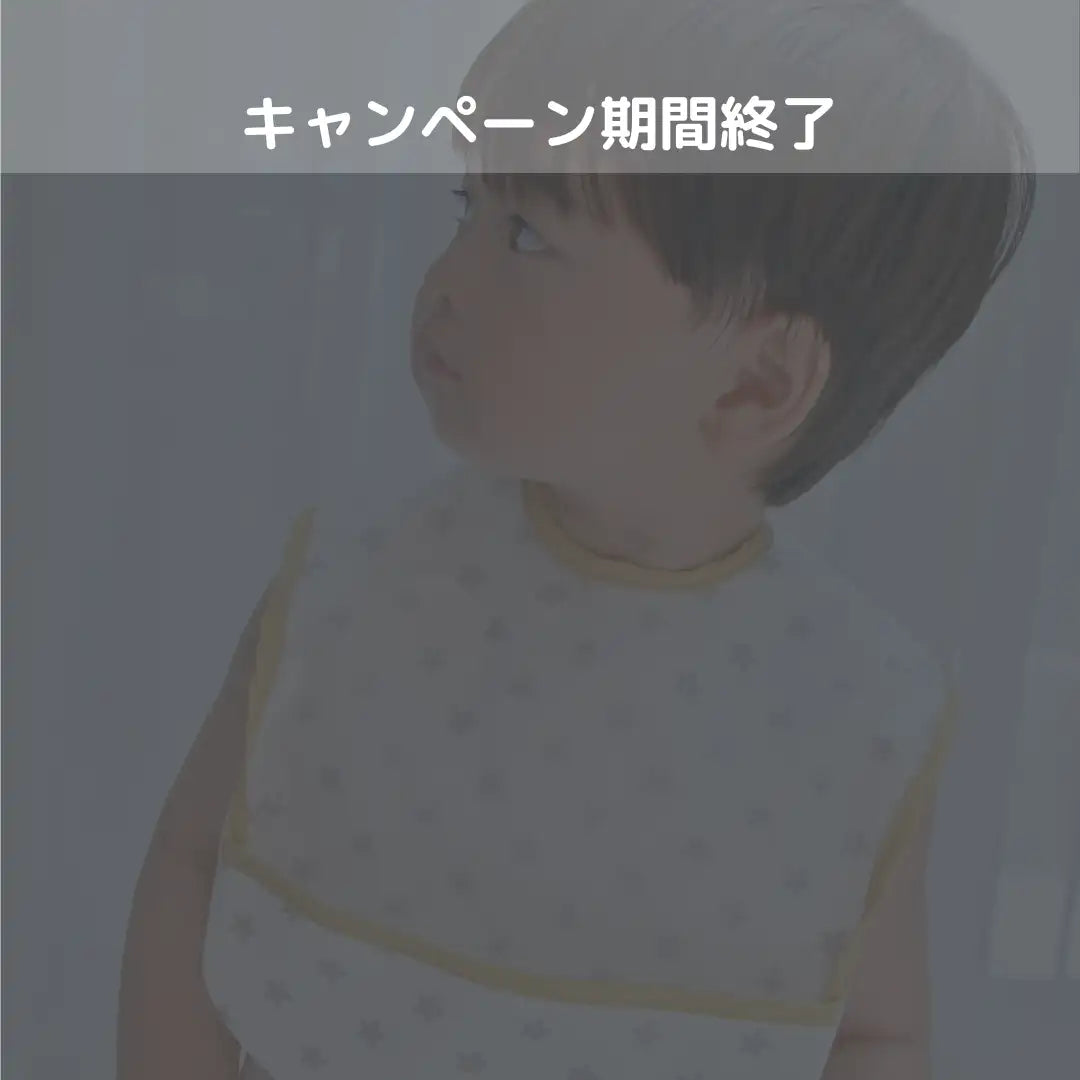 小さな灰色の水玉模様と黄色い縁取りの白いよだれかけを着けた子供。